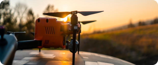 Orange drone at sunset on vehicle.