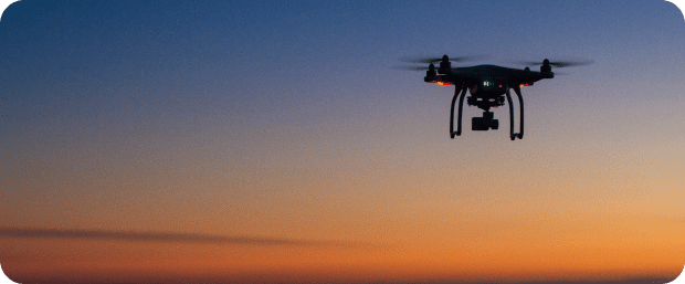 Here's an alt tag for the image: Drone flying at sunset.