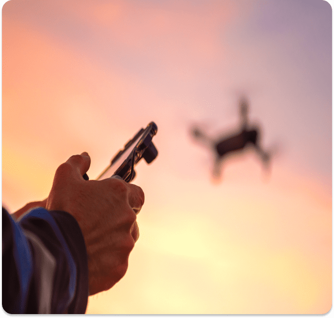 Here's an alt tag for the image: Person flying drone at sunset.