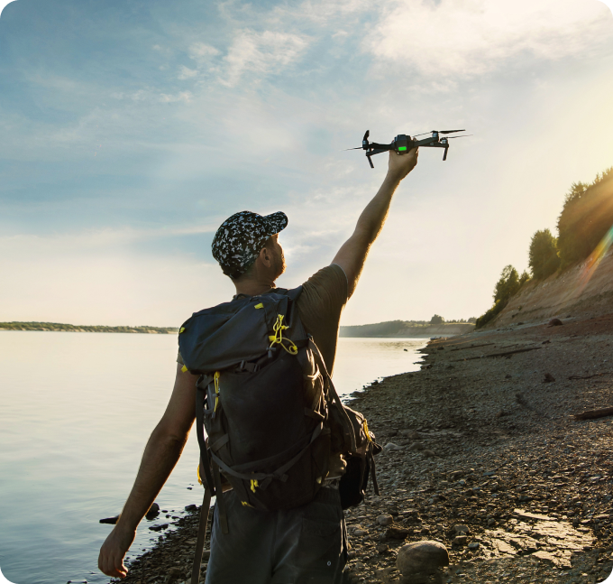 Man launches drone by lake.