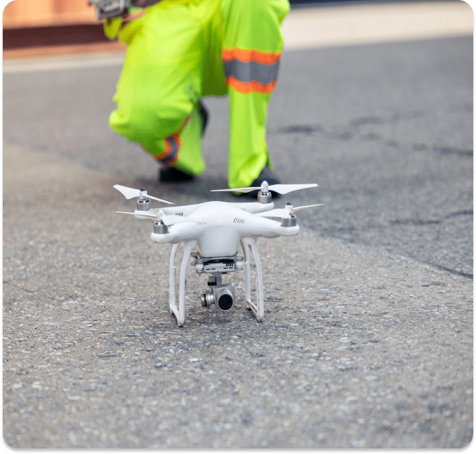 Here's an alt tag for the image: White drone on pavement near worker.